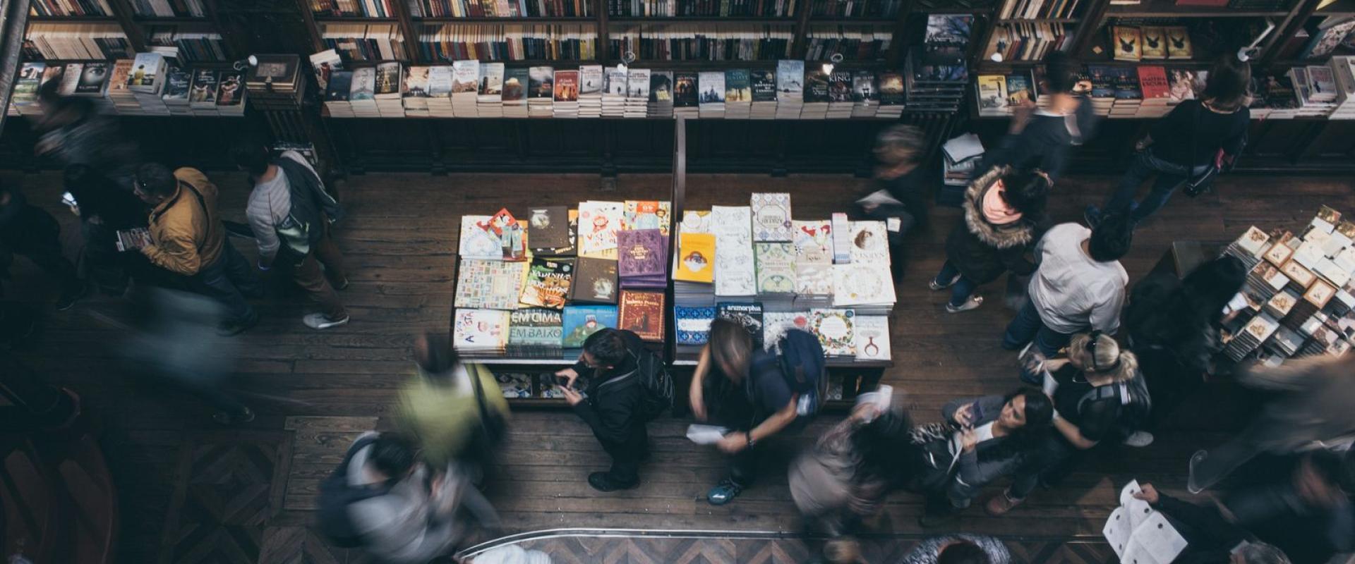 Busy bookstore scene in Porto, Portugal, with people browsing shelves and blurred motion capturing the dynamic atmosphere.