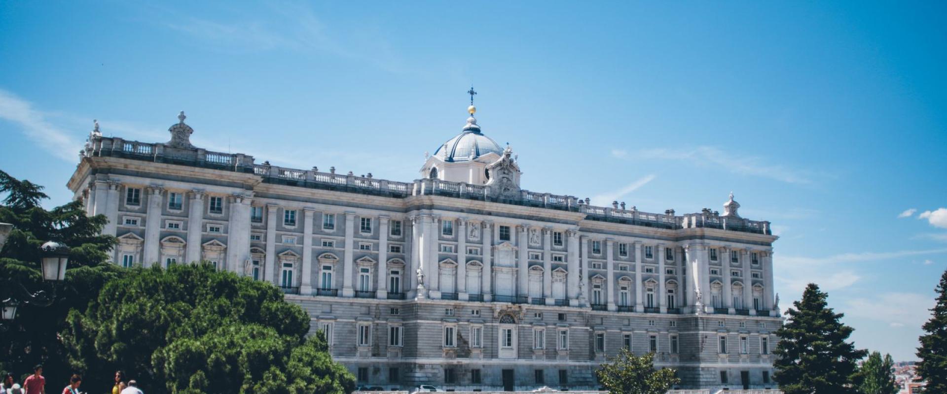 Free Stunning view of the Royal Palace of Madrid with surrounding greenery and tourists below. Stock Photo