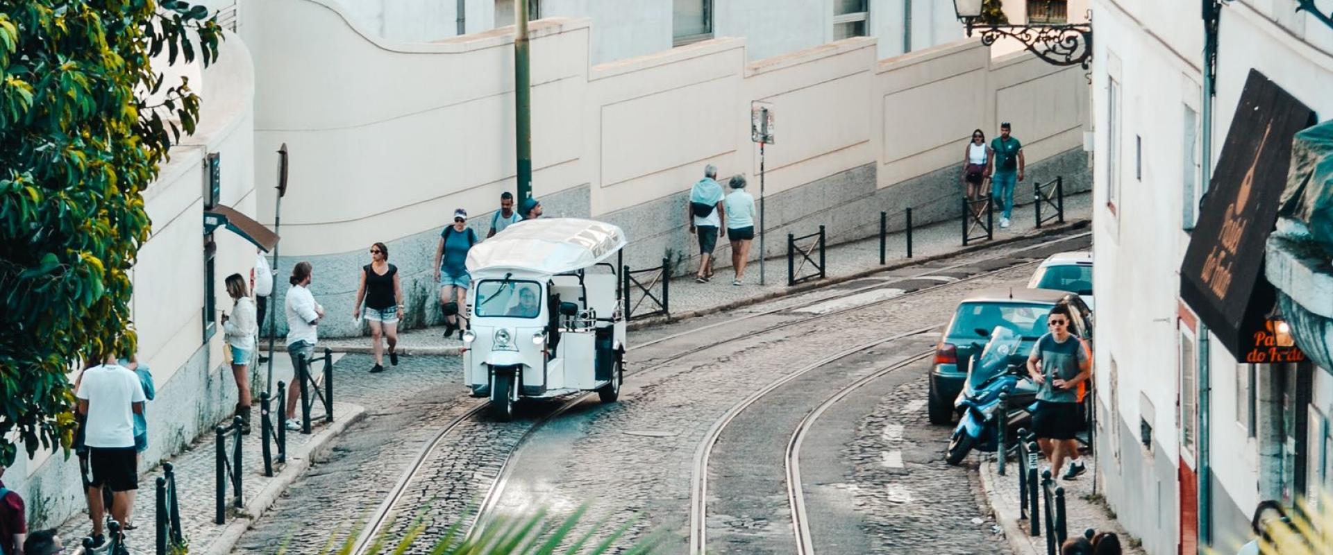 Picturesque cobblestone street with tram lines and lush greenery in a historic Portuguese town.