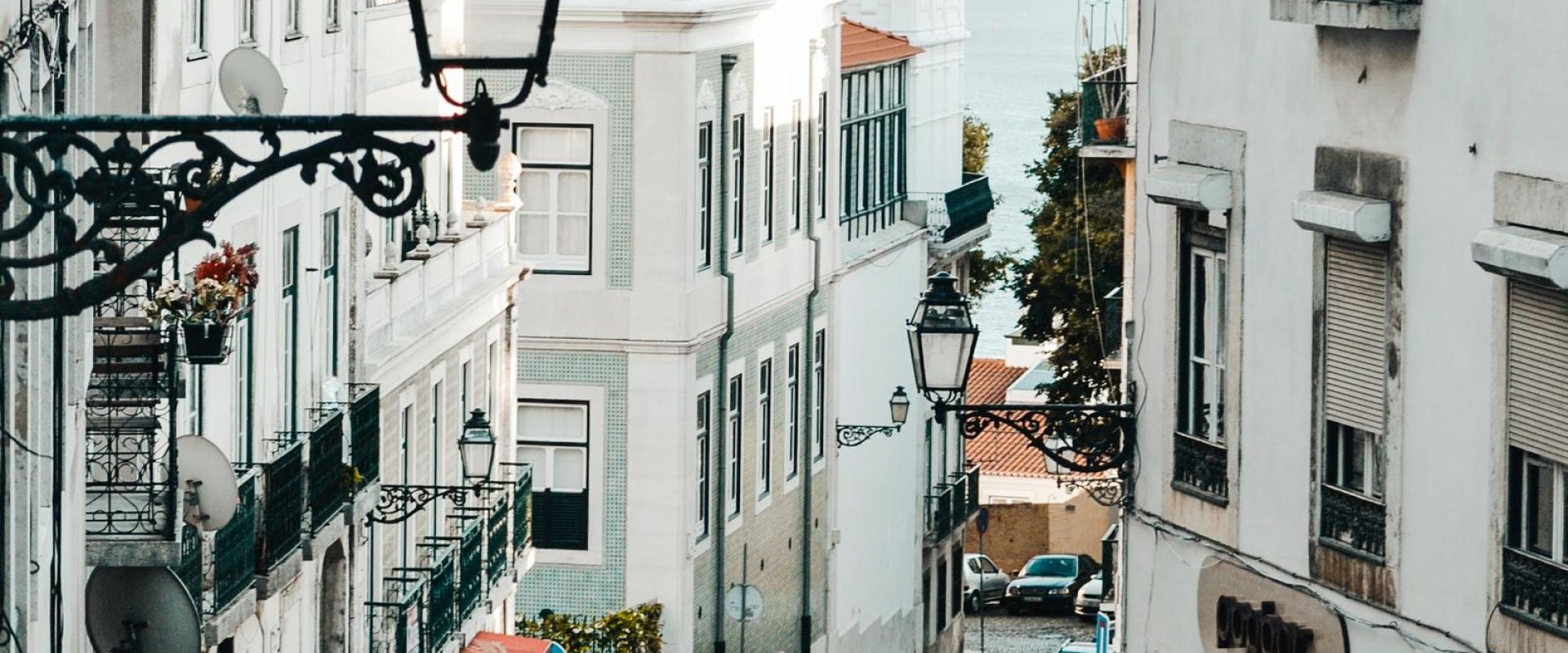 Explore a picturesque cobblestone street in Lisbon's historic district, alive with vibrant local life.