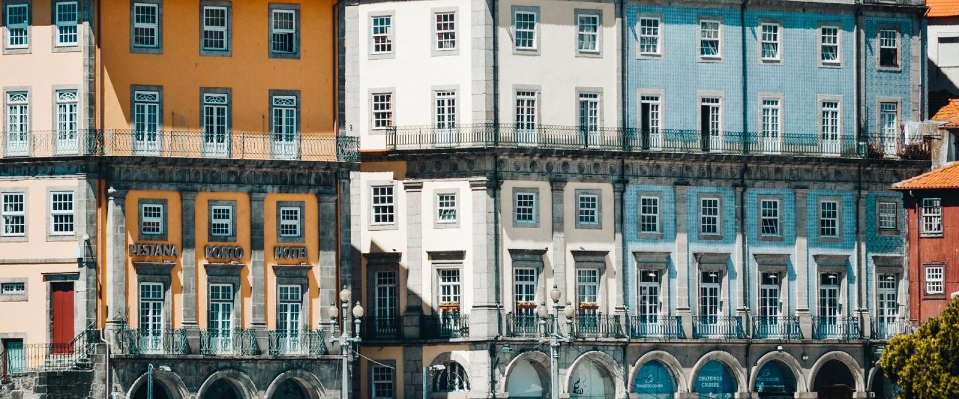 Colorful buildings of Porto's Ribeira district on a sunny day with tourists below.