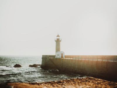 A stunning view of Porto's lighthouse, captured with the sea and sunset in the background.