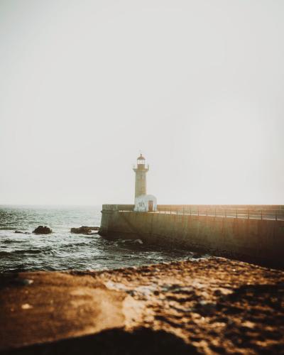A stunning view of Porto's lighthouse, captured with the sea and sunset in the background.