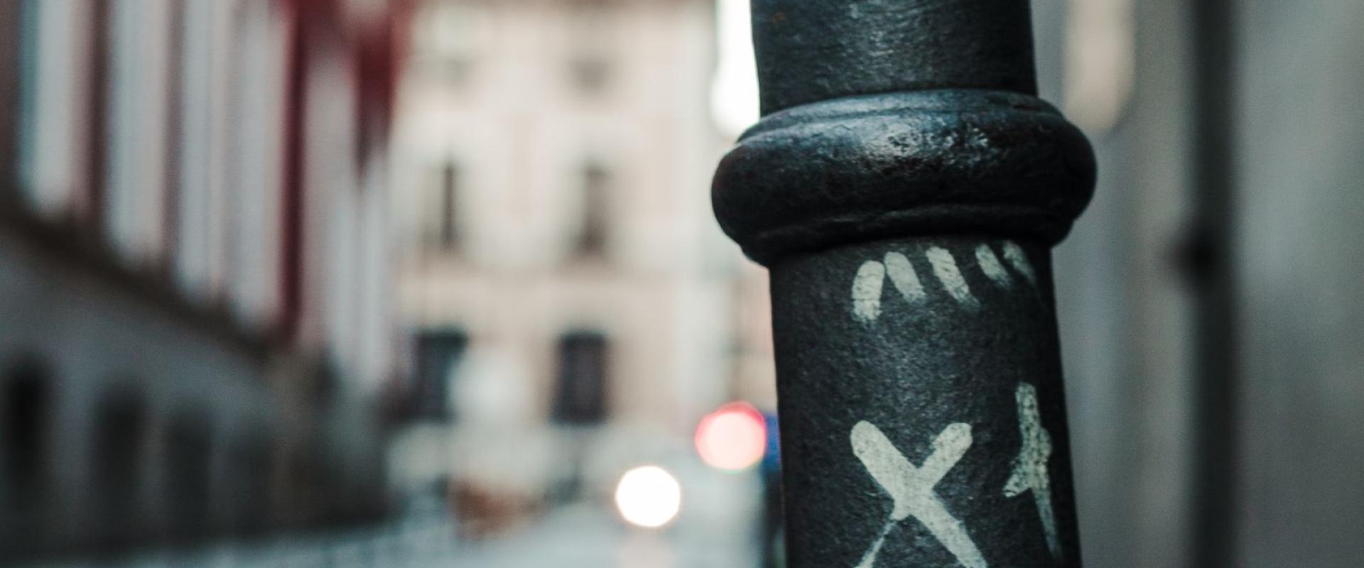 Free Urban street scene in Madrid featuring graffiti on metal pole with blurred architectural background. Stock Photo