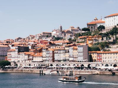 Charming view of Porto's Ribeira district and Douro River with a scenic boat under a clear sky.
