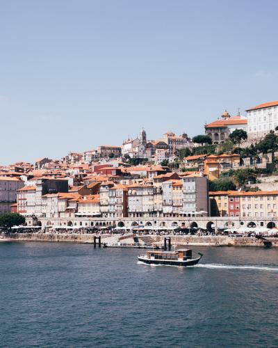 Charming view of Porto's Ribeira district and Douro River with a scenic boat under a clear sky.