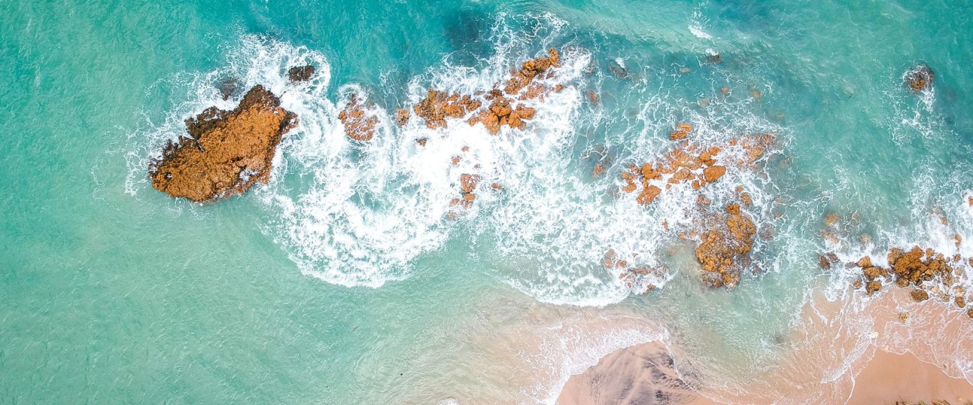 Free Stunning aerial shot of a Brazilian beach with turquoise waters and rocky coastline. Stock Photo