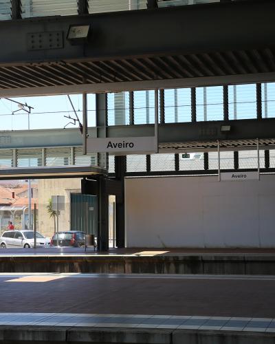A view of a train station platform with overhead signage clearly reading "Aveiro" and "Aveiro" on the platform wall.