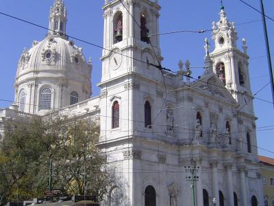 Facade and dome of Basilica da Estrela in Lisbon with a yellow tram passing