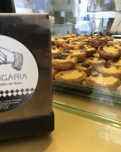 Trays of pasteis de nata beside the Manteigaria logo in Lisbon
