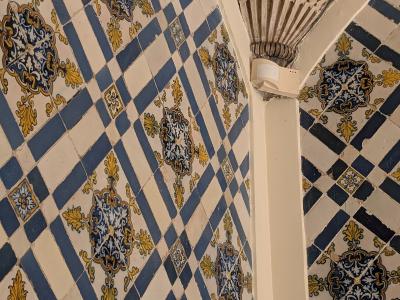 Close-up view of blue, white, and yellow patterned azulejo tiles covering the walls and arches of a historic interior, featuring a stone column capital.