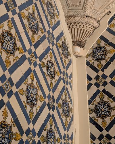 Close-up view of blue, white, and yellow patterned azulejo tiles covering the walls and arches of a historic interior, featuring a stone column capital.