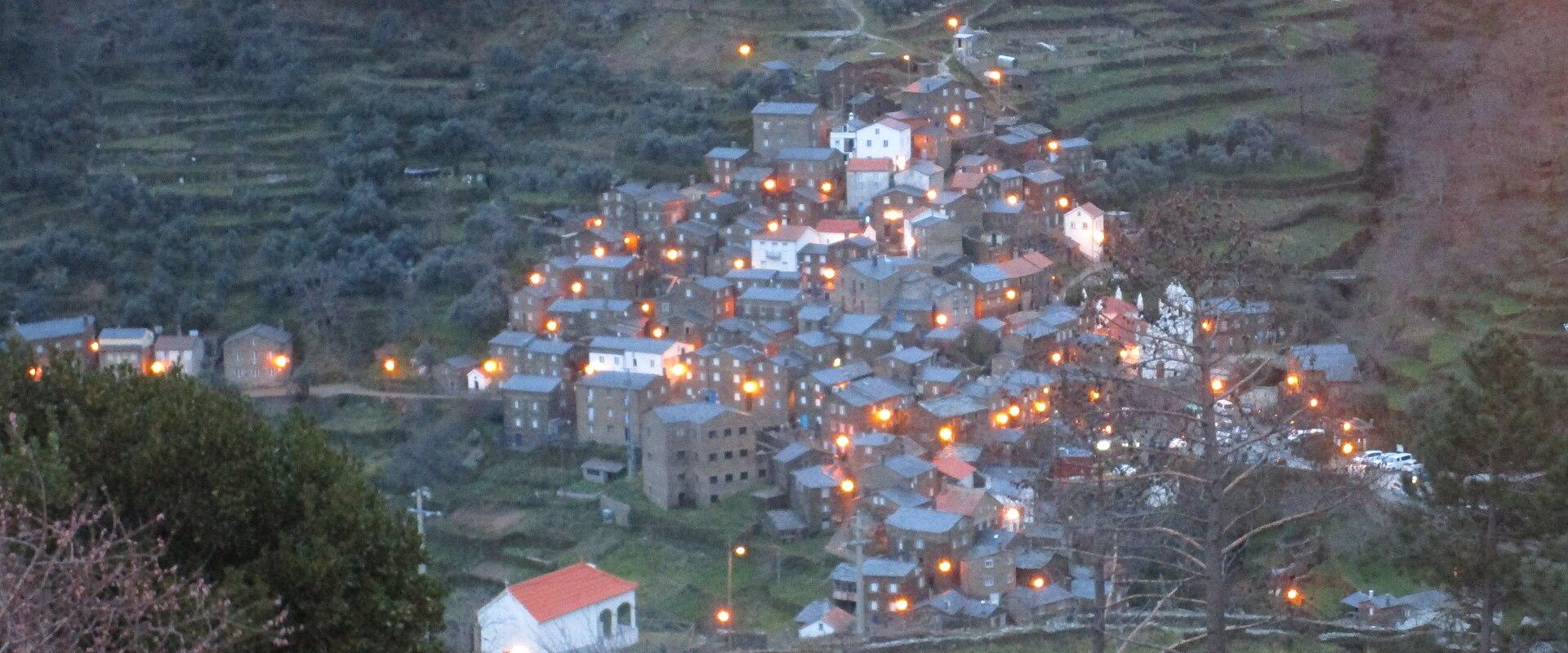 The schist village of Piódão lit up at dusk on a terraced hillside in the Beira mountains