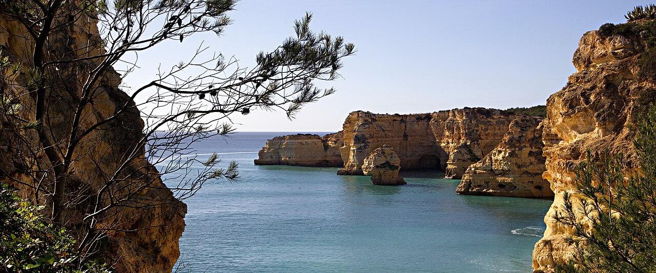 Golden limestone cliffs and a turquoise cove at Praia da Marinha in the Algarve