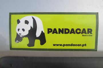 A close-up of a yellow and green rectangular sticker on a car surface, featuring a black-and-white panda logo, the text "PANDACAR Rent a Car", and the website "www.pandacar.pt".