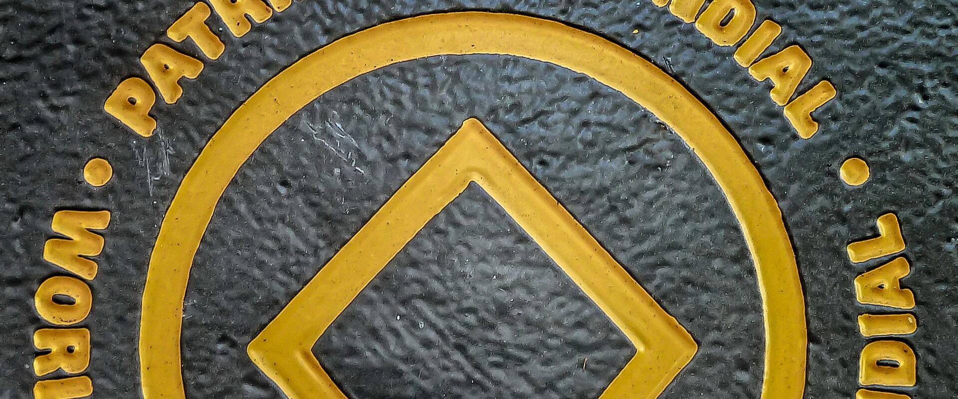 A close-up of a textured black plaque featuring raised gold lettering and the UNESCO World Heritage logo, with the word "PORTO" at the top and multilingual text ("PATRIMONIO MUNDIAL", "WORLD HERITAGE", "PATRIMOINE MONDIAL") surrounding the central sy