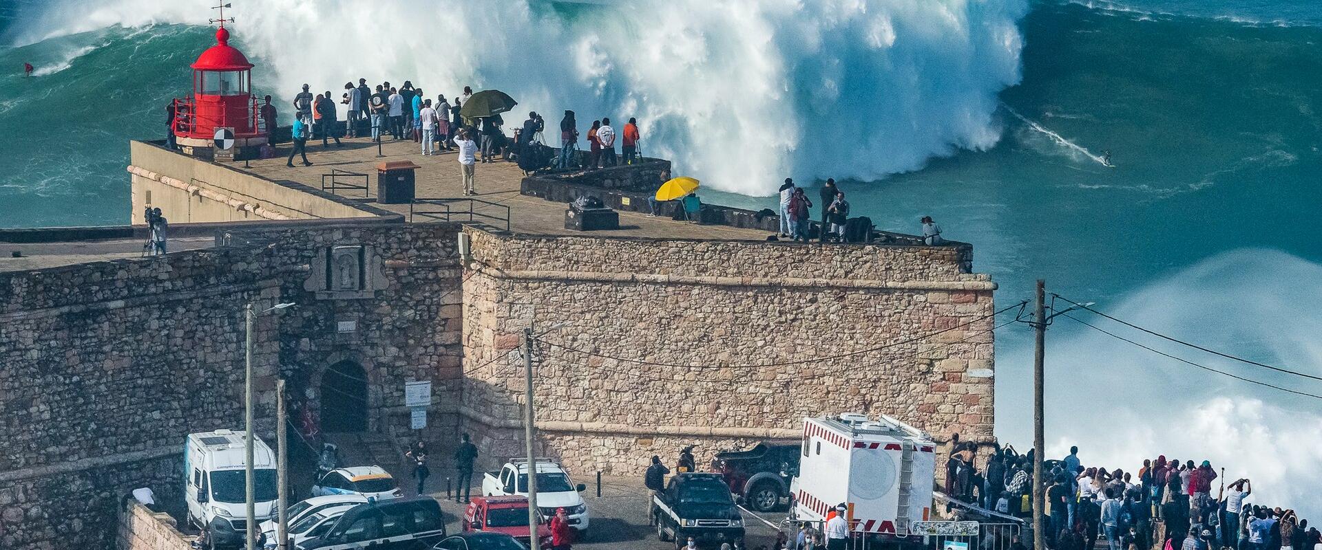 Giant wave breaking at Praia do Norte watched by crowds at the Nazaré fort