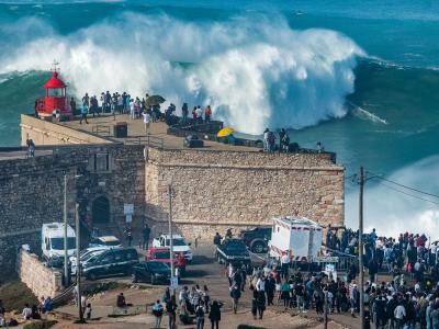 Giant wave breaking at Praia do Norte watched by crowds at the Nazaré fort