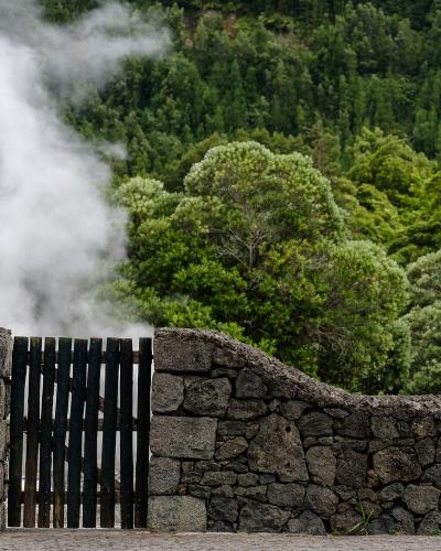 Steam rising over the volcanic stone wall at Furnas hot springs, Sao Miguel, Azores