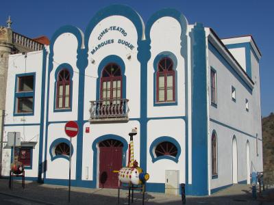 A white and blue building with Moorish-style arches and signage reading "CINE-TEATRO MARQUES DUQUE" on its facade.