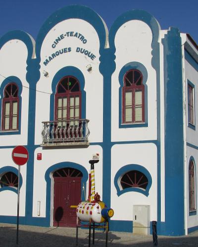A white and blue building with Moorish-style arches and signage reading "CINE-TEATRO MARQUES DUQUE" on its facade.
