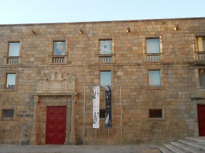 A stone building facade with red doors, banners, and a sign reading "MUSEU GRÃO VASCO" on the wall.
