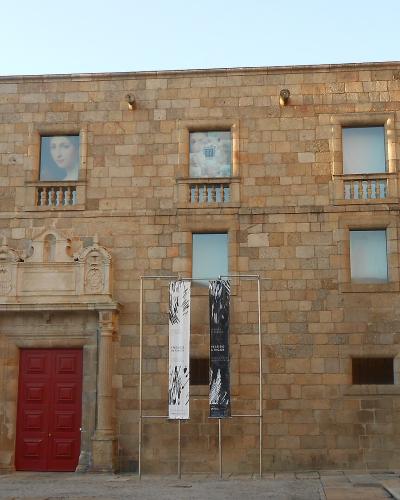 A stone building facade with red doors, banners, and a sign reading "MUSEU GRÃO VASCO" on the wall.