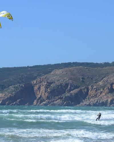 Atlantic surf and kitesurfers at Praia do Guincho below the Sintra hills