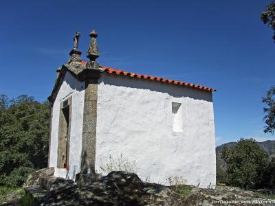 A whitewashed chapel of the São Salvador do Mundo sanctuary among trees above the Douro
